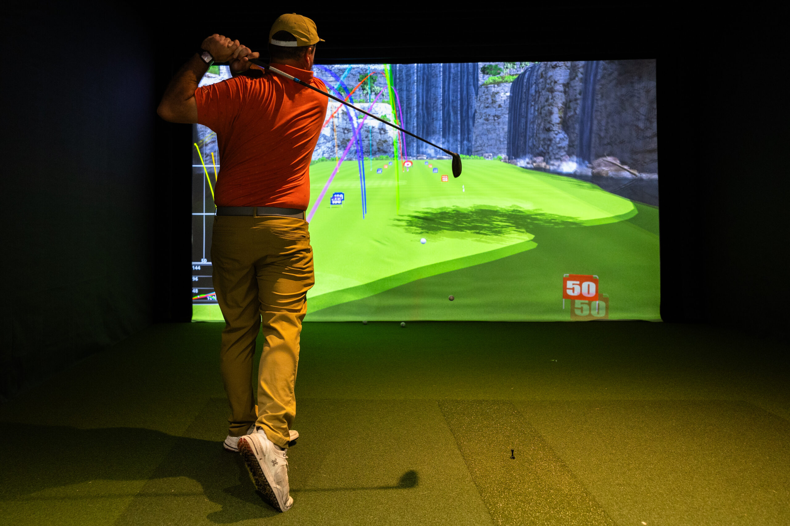 Man golfing in a golf simulator.